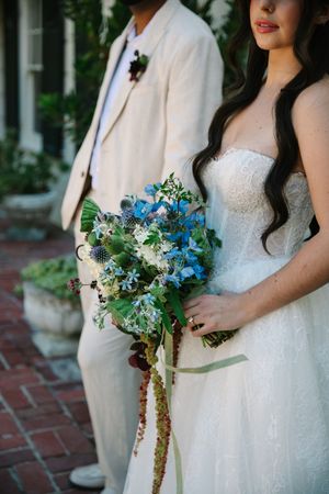 Elegant white wedding dress with blue floral bouquet details shown in three similar bridal detail shots.