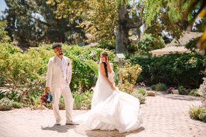 Newlyweds walking through a lush garden path during a romantic outdoor celebration.