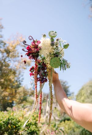 Whimsical floral arrangements being held up against bright blue sky.