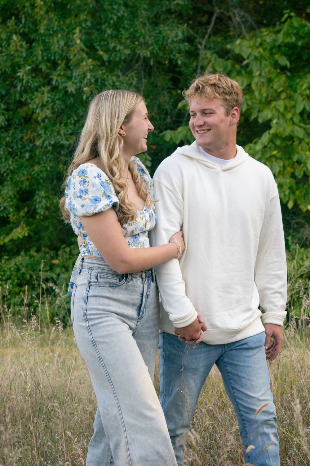 Couple walking through field laughing