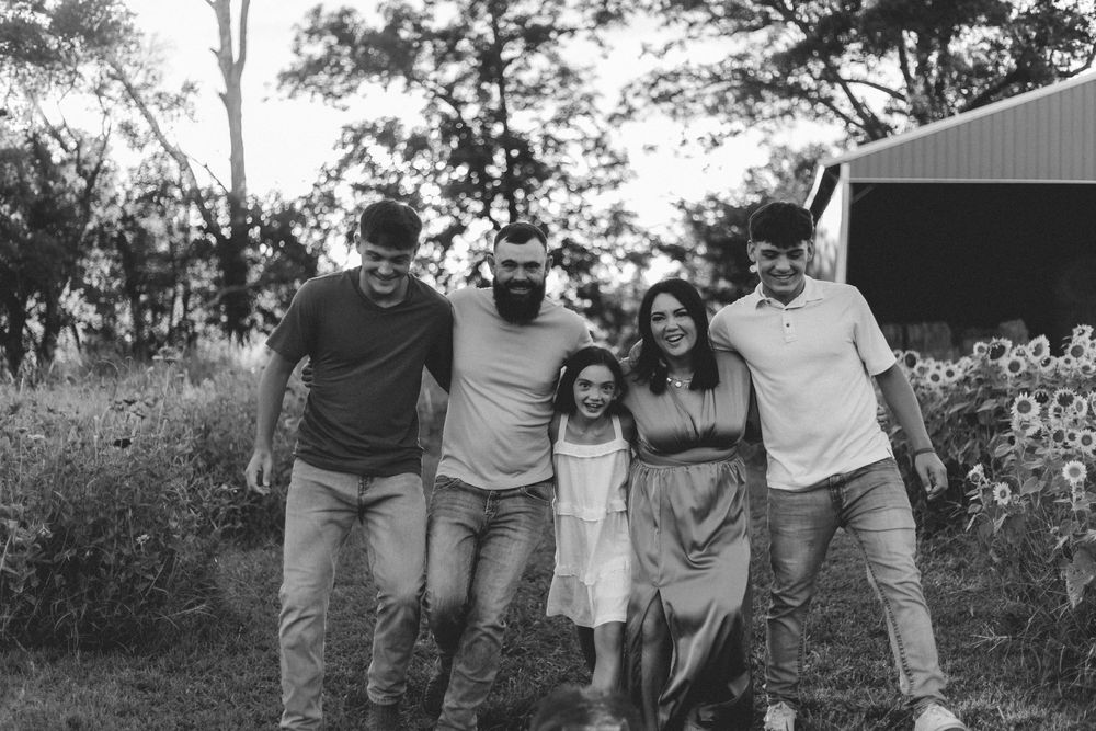 A group of people walking arm in arm through a grassy outdoor area.