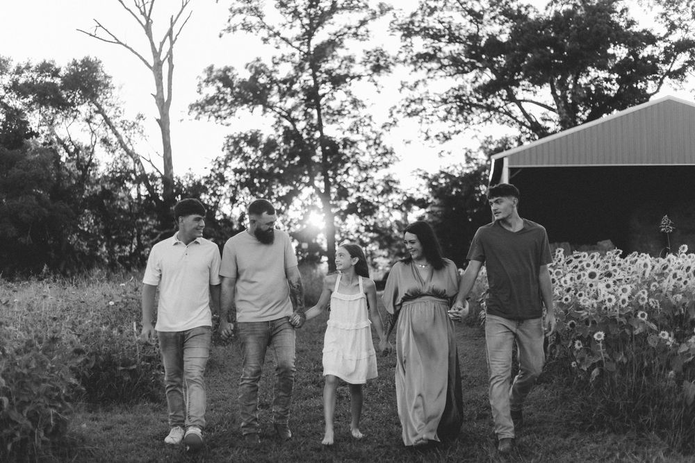 A group of people walking together through a flower garden in a scenic black and white photograph.