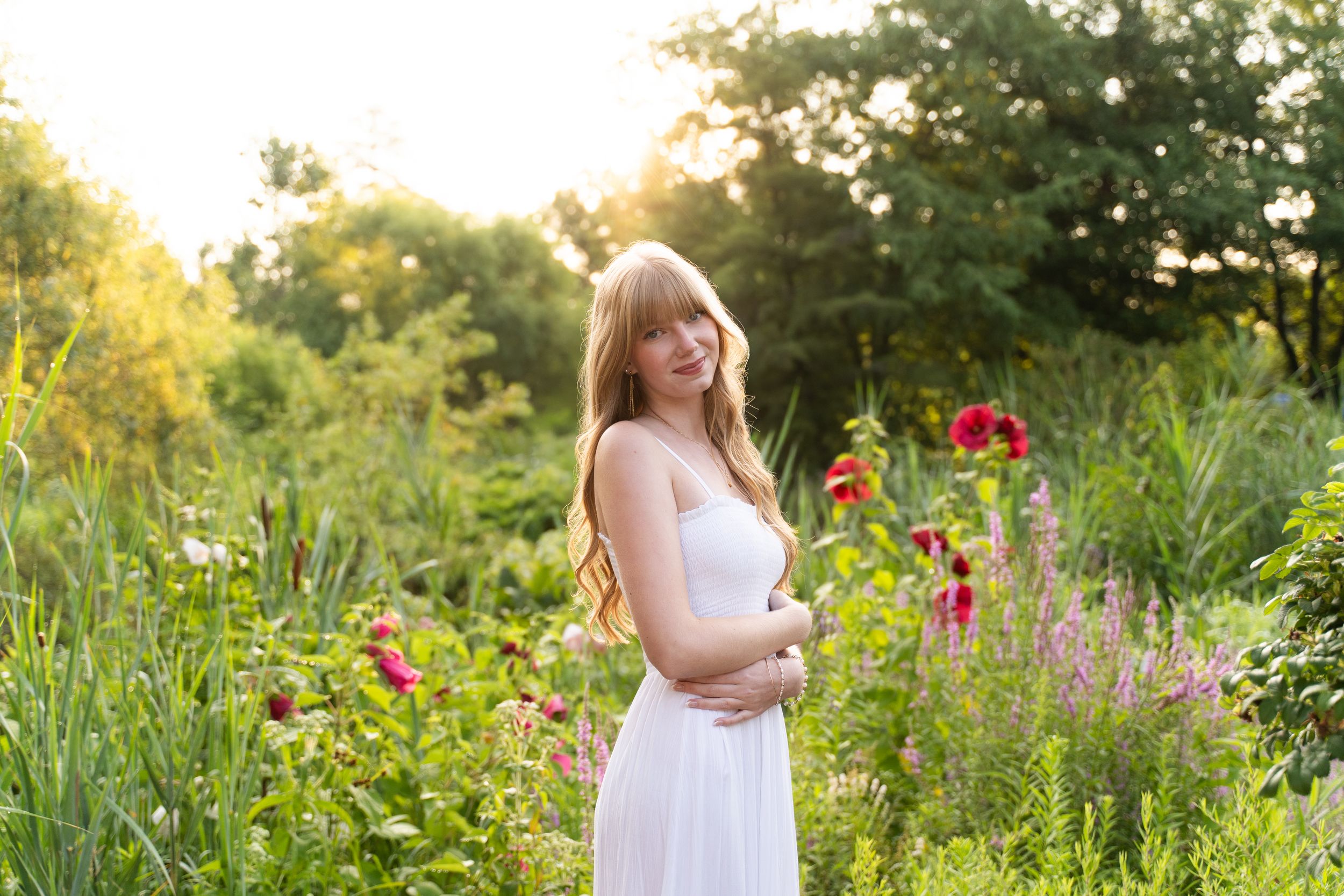 Child in white dress explores vibrant wildflower garden at golden hour in summer.