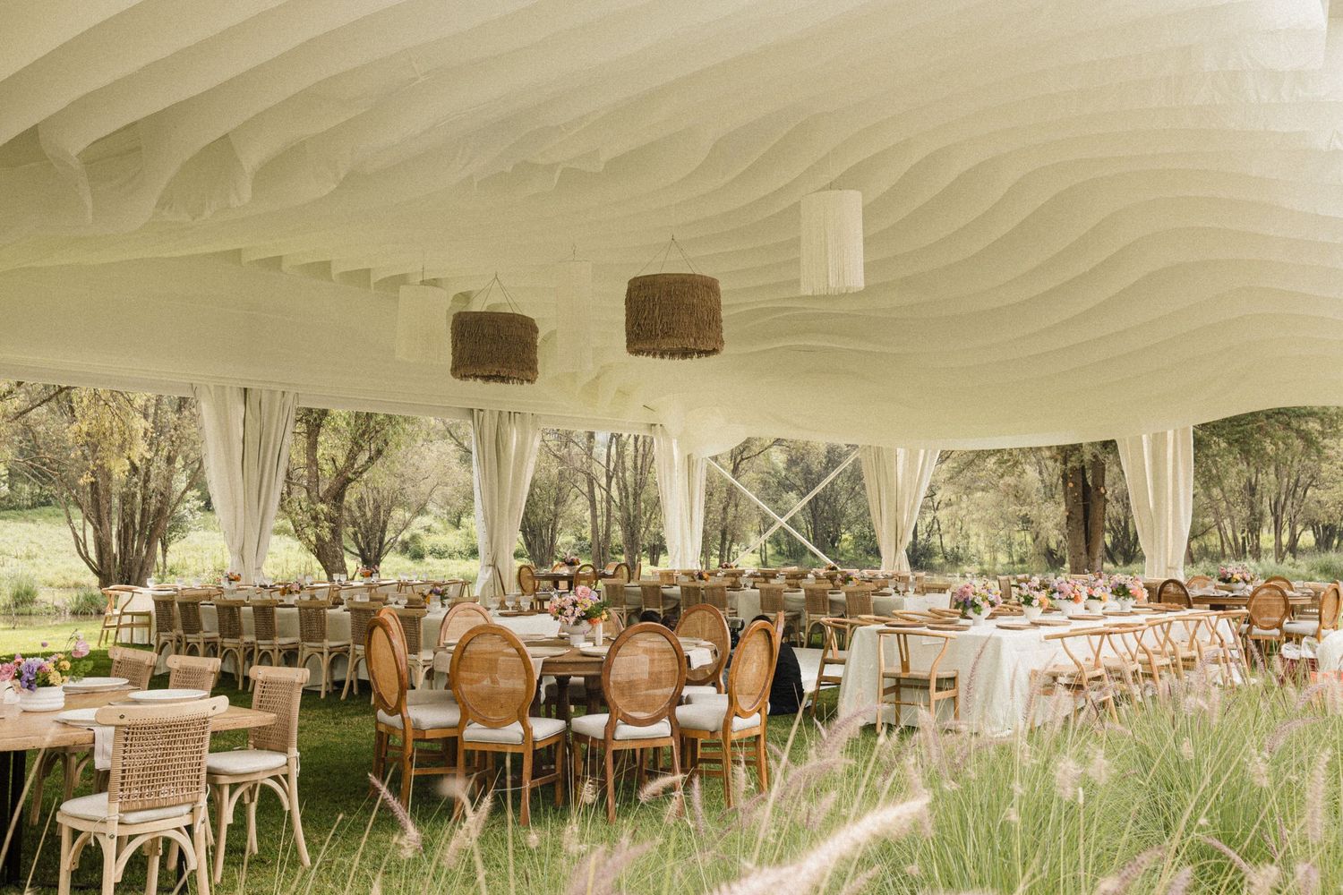 Wedding reception tent decorated with flowing white fabric and elegant table settings.