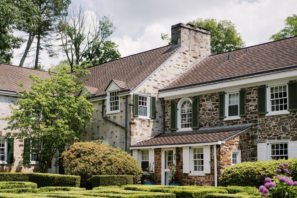 A collage of exterior views showing different angles of a stone and brick house with traditional architectural features.