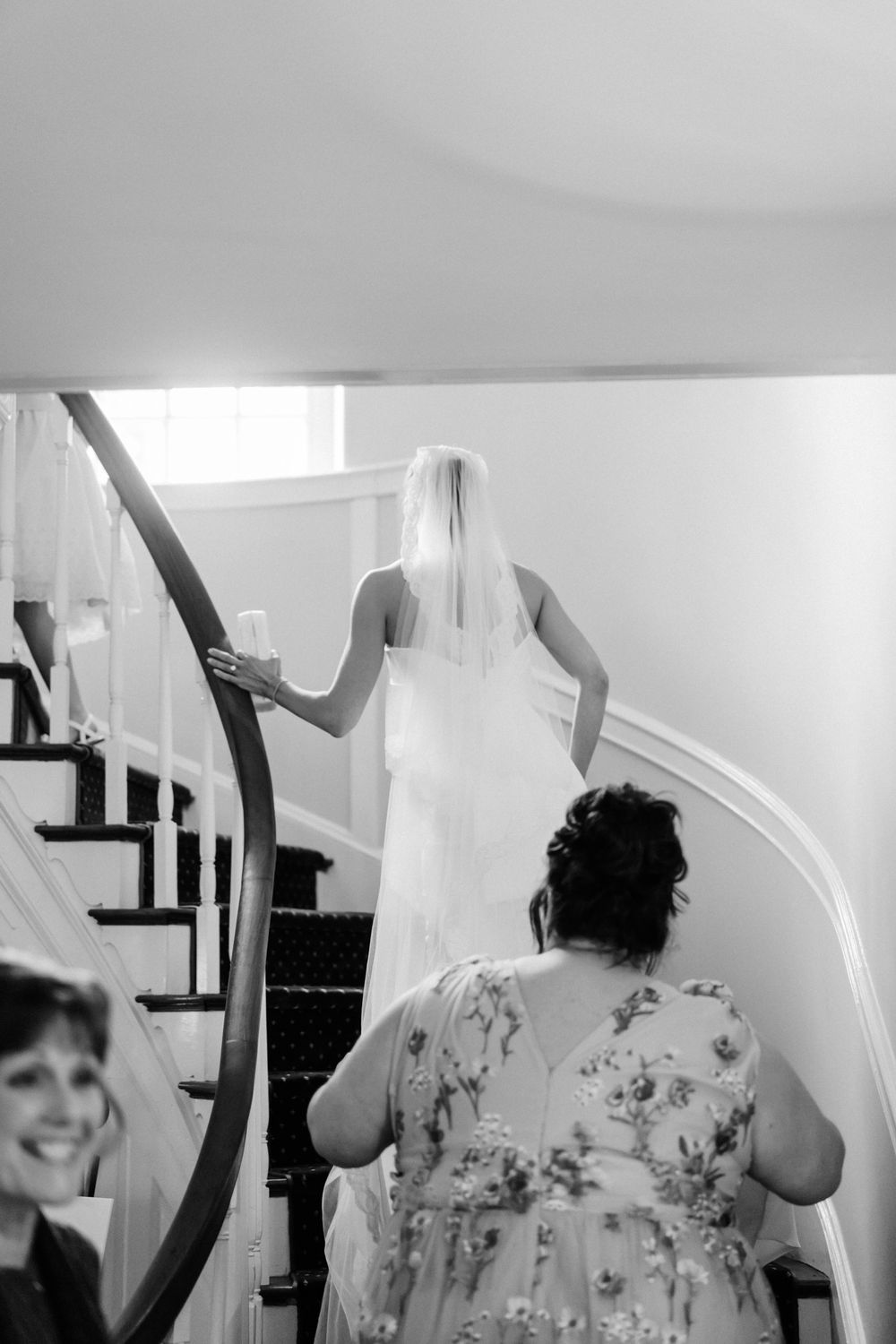 Interior staircase scene with flowing white wedding dress fabric being arranged.