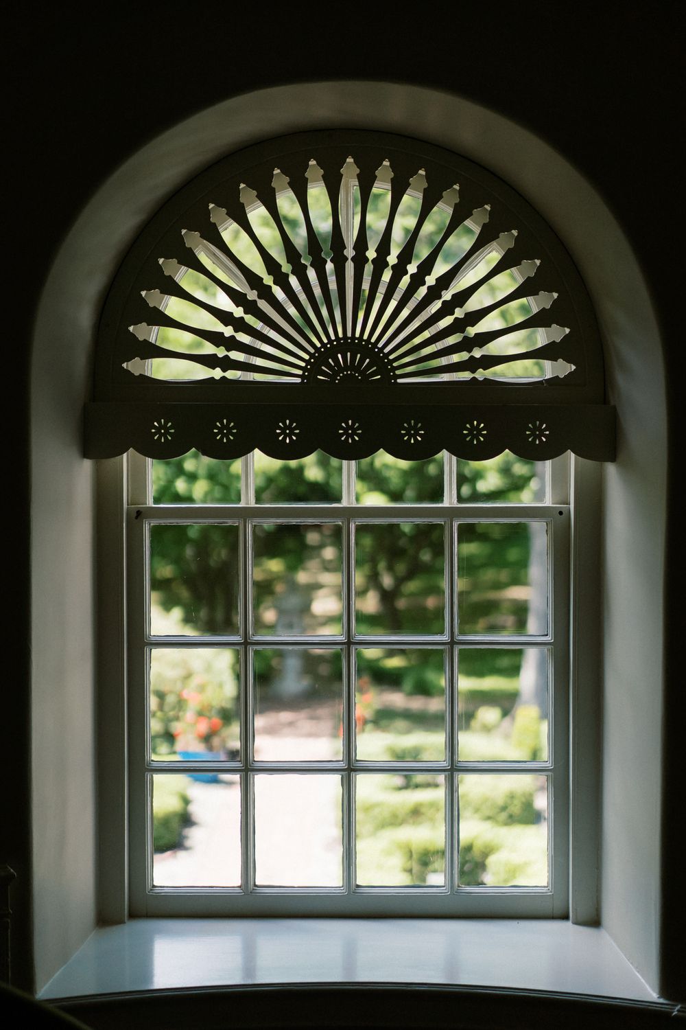 Elegant fan-shaped window treatments adorn arched windows in a historic building.