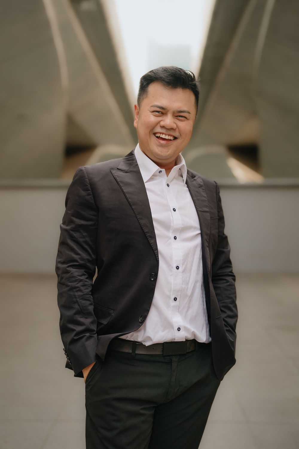 A professional wearing a black suit and white dress shirt poses progressively across multiple similar photos outdoors.