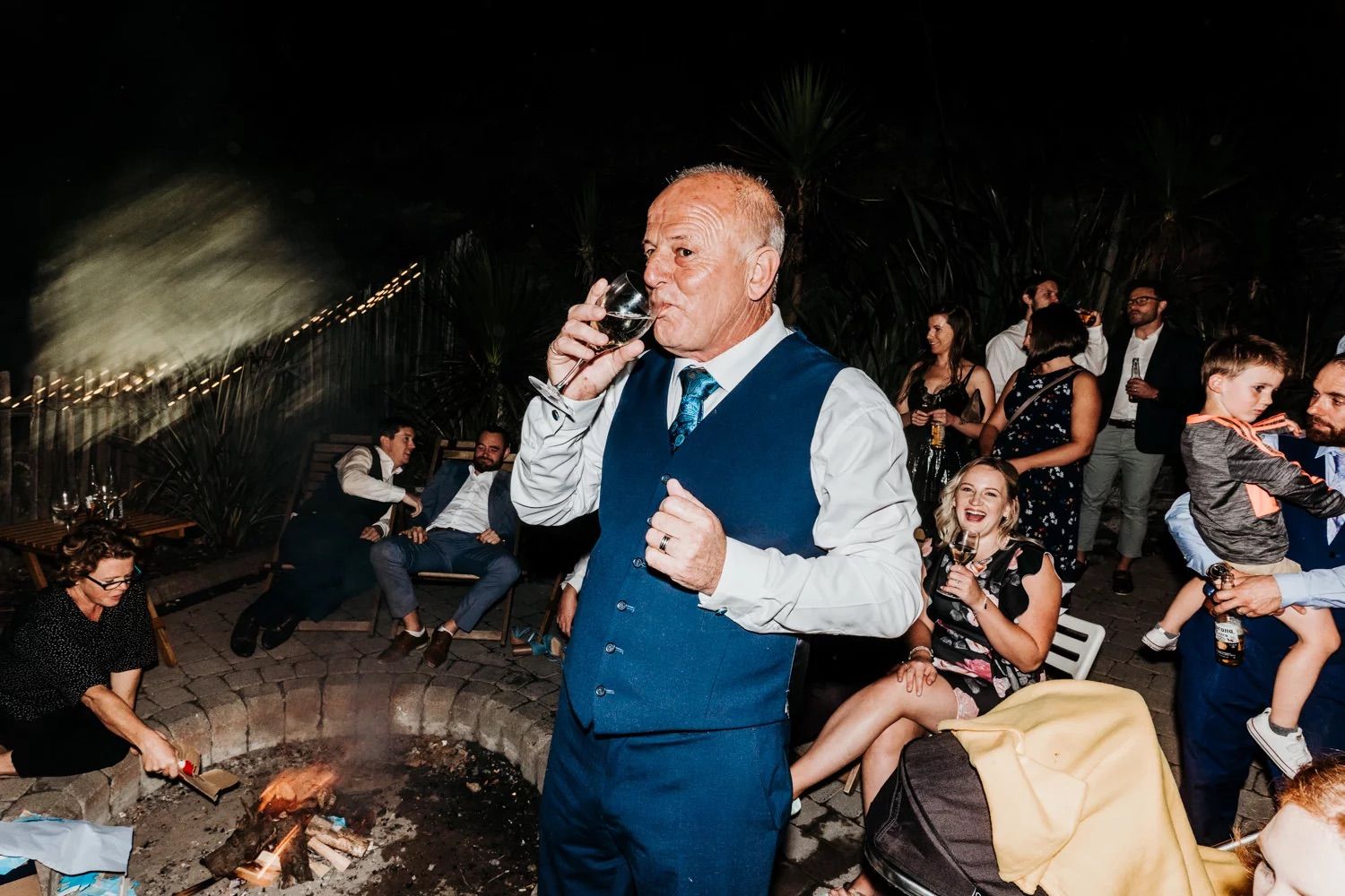 Lively wedding reception scene with guests dancing and celebrating in the evening.