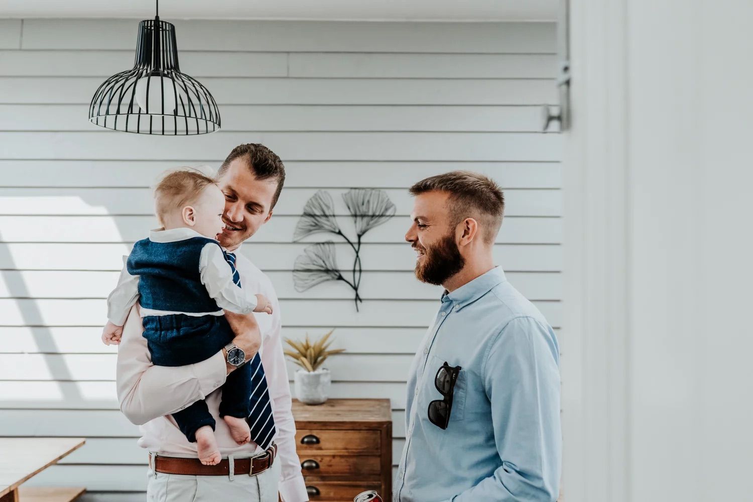 Joyful gathering in a bright modern space with white shiplap walls and lighting fixtures.