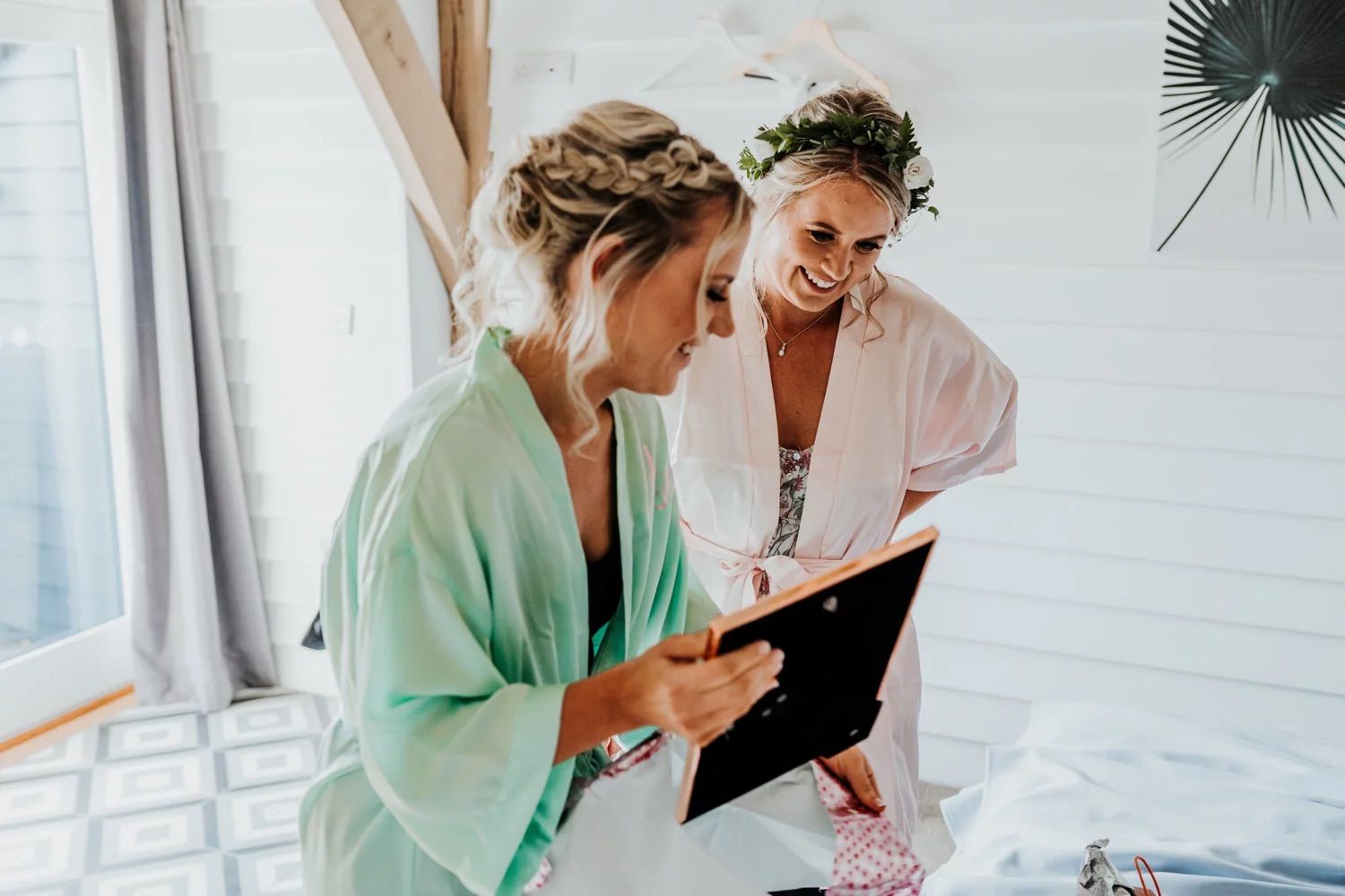 Two people sharing a cheerful moment while looking at documents in a bright sunlit room.