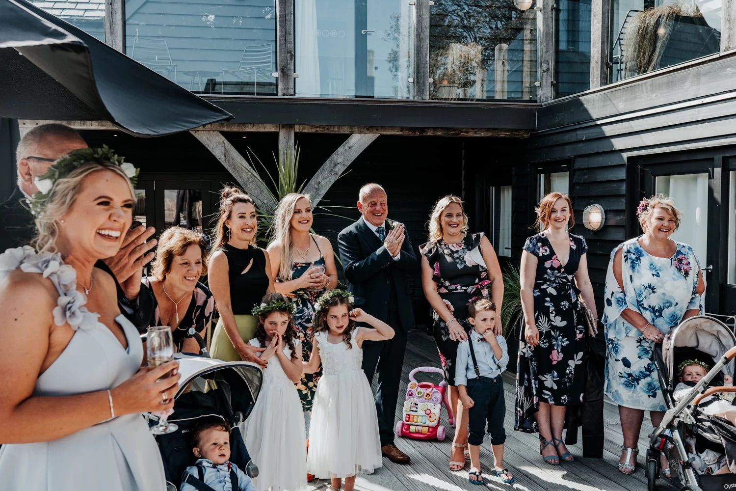 Wedding guests gather outside on a covered patio area during a celebration event.