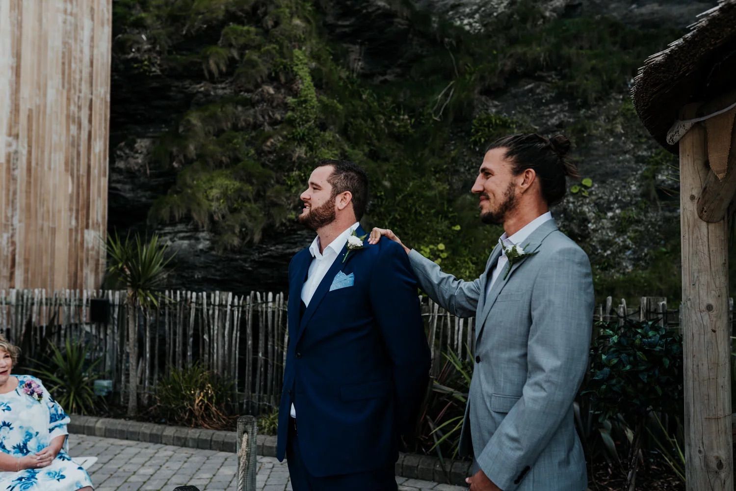 Wedding ceremony setup with chairs and white banners on a rocky coastal hillside.