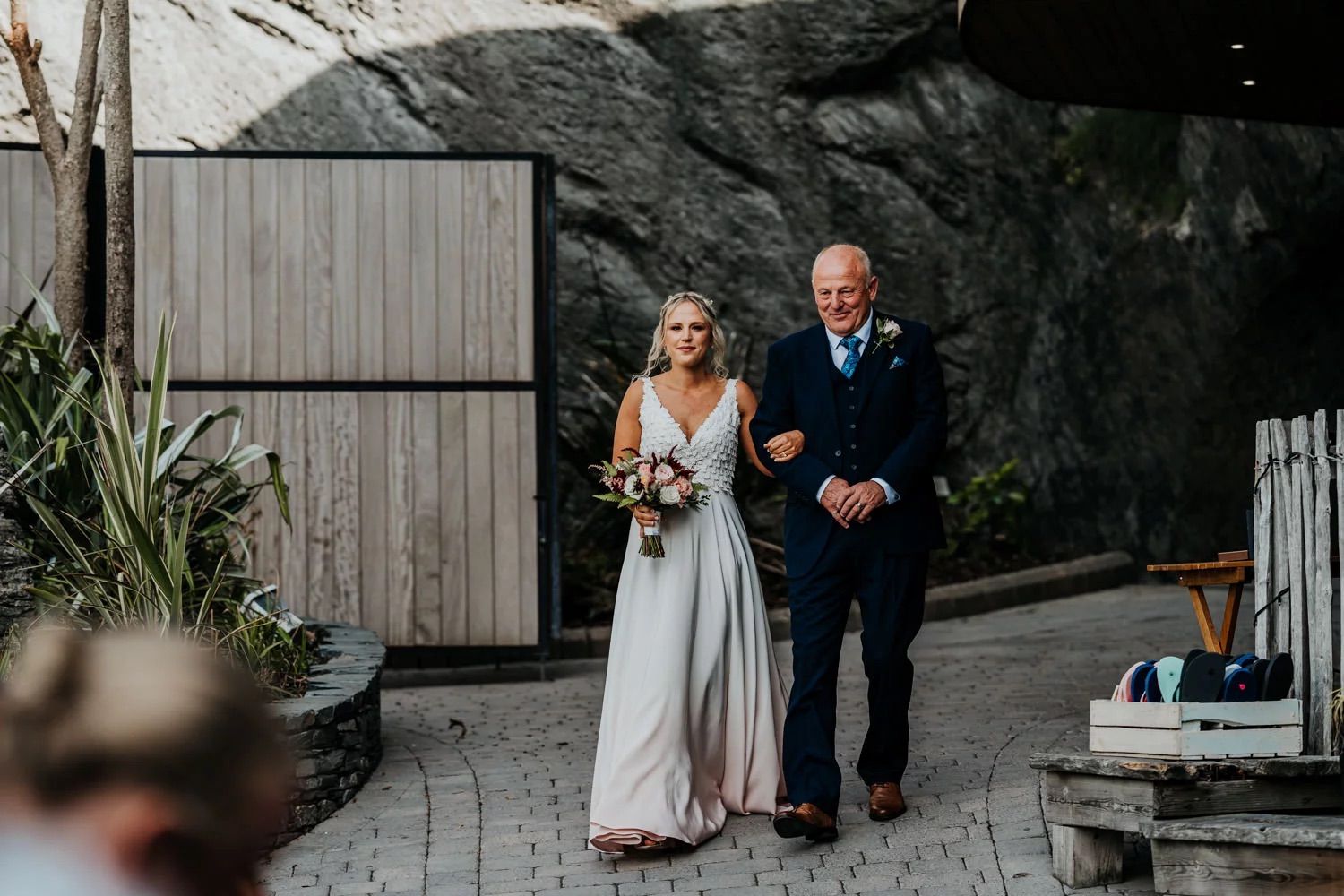 A couple walks together on a stone path at dusk with a moody atmosphere.