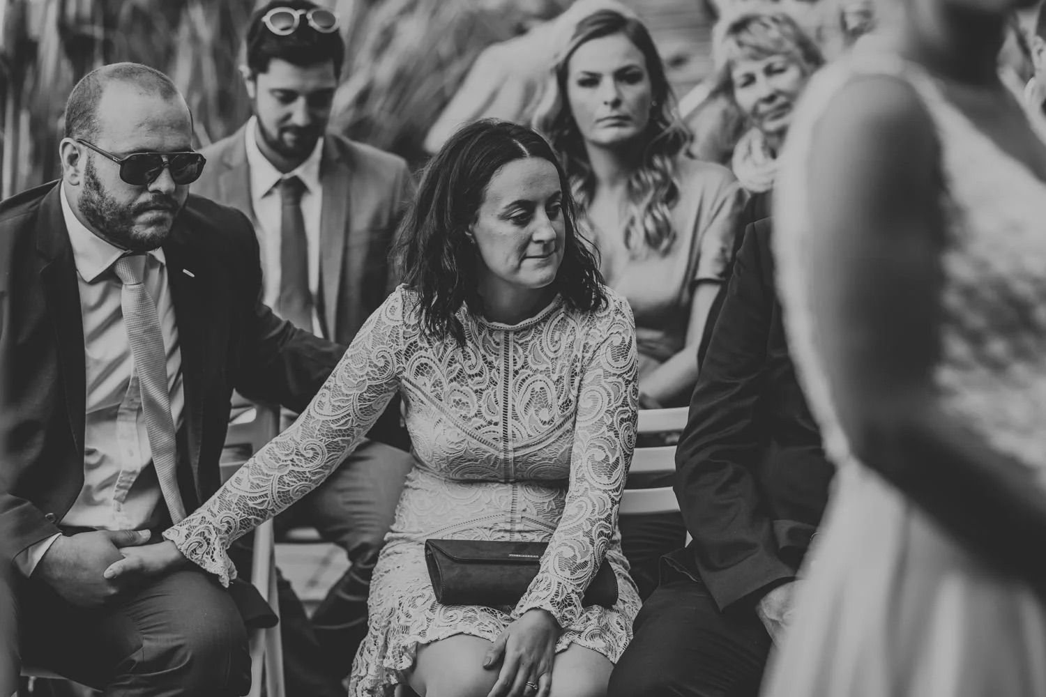 Black and white photo of wedding guests seated during an indoor ceremony.