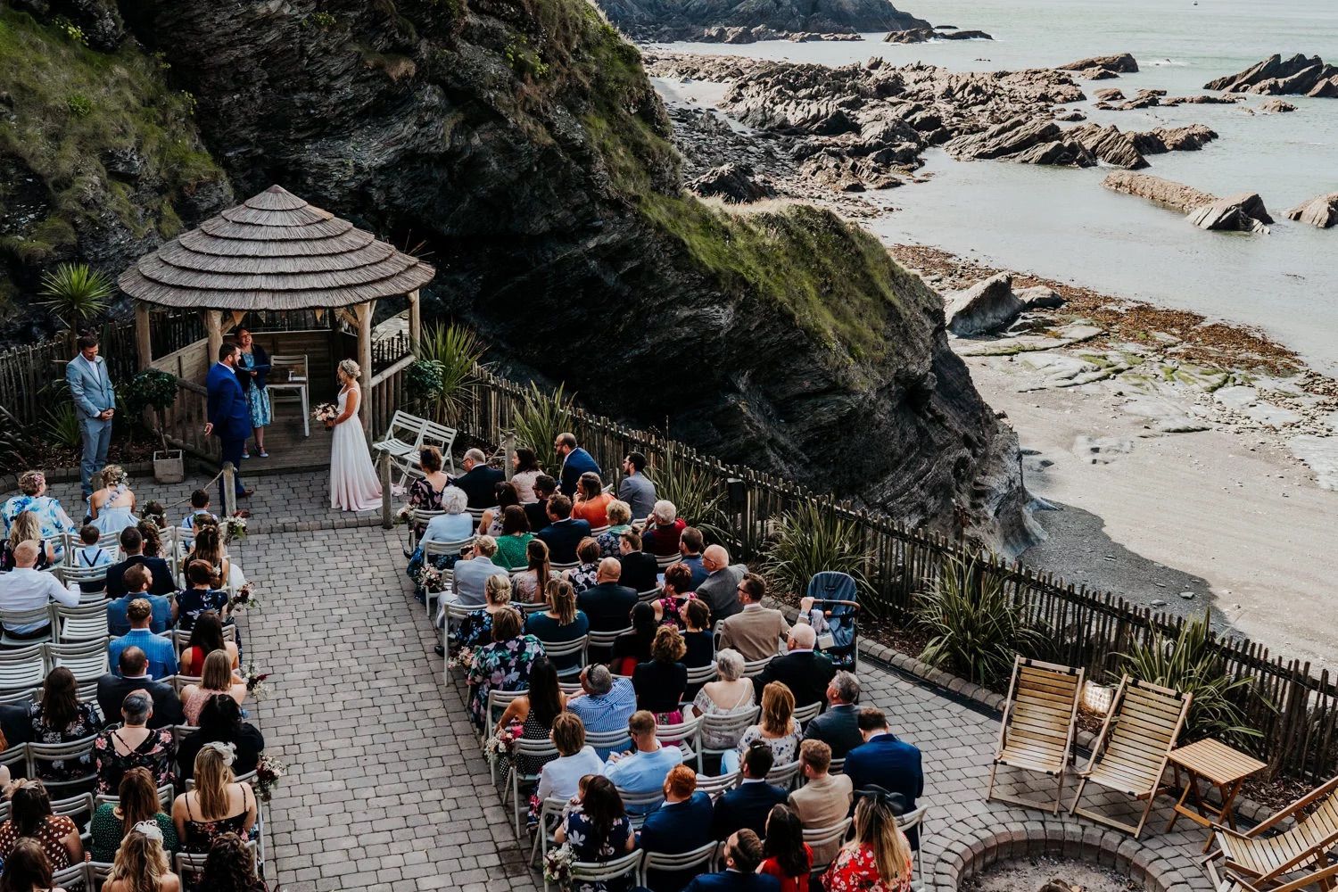 Wedding guests seated outdoors overlooking a dramatic coastal landscape.