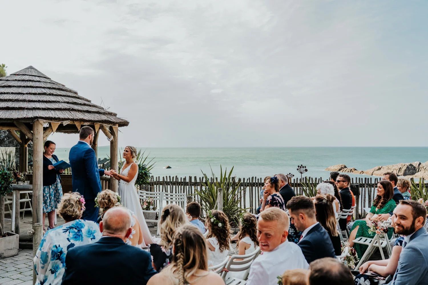 Event attendees gather at a waterfront venue under cloudy skies.