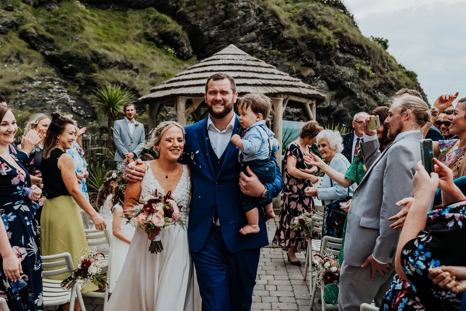 Outdoor wedding ceremony with mountain backdrop and white gazebo surrounded by guests.