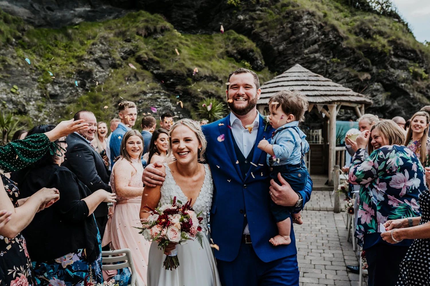 Emotional wedding celebration with guests gathered on rocky coastal terrain.