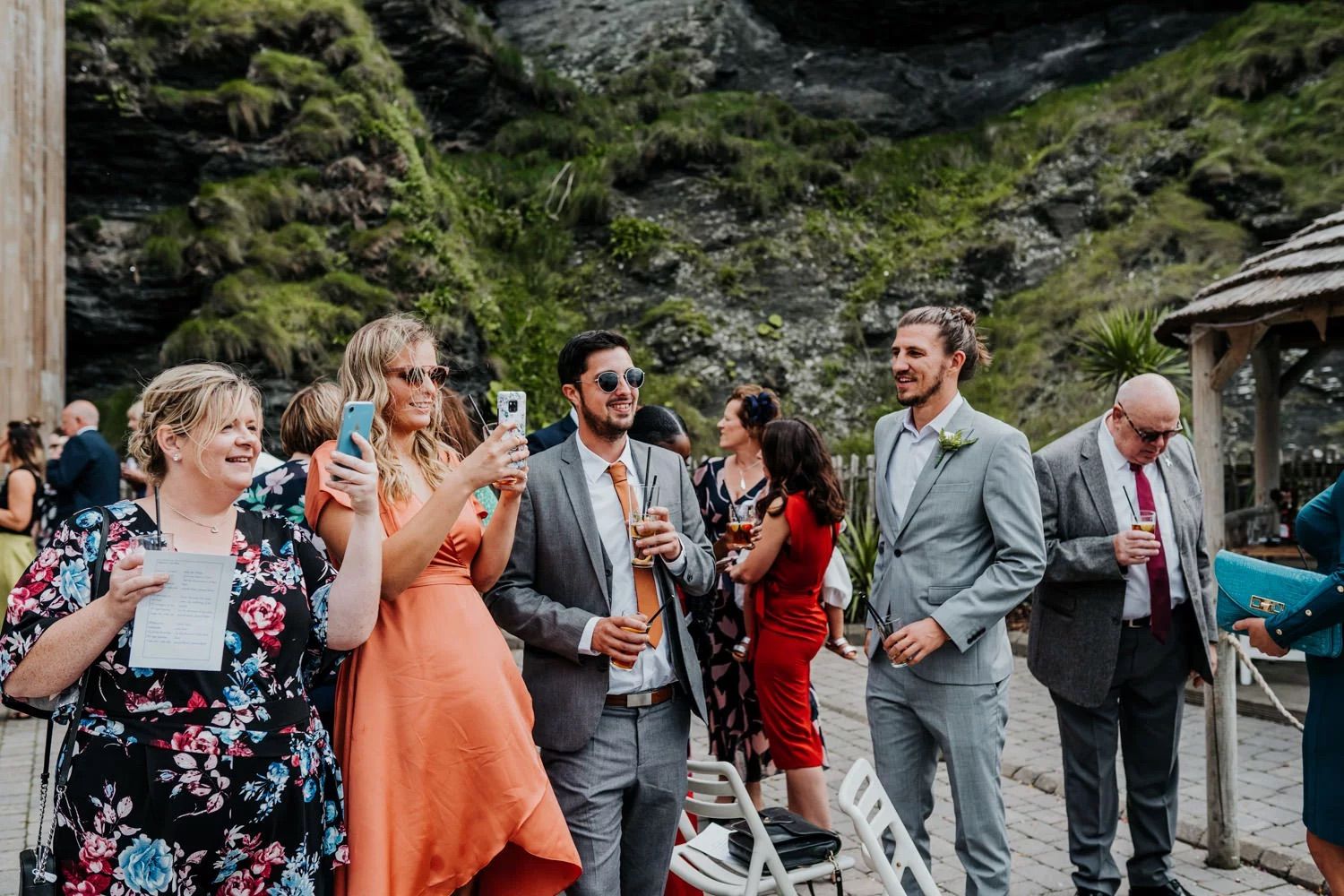Wedding guests gather outdoors in a scenic mountain landscape for group photos.
