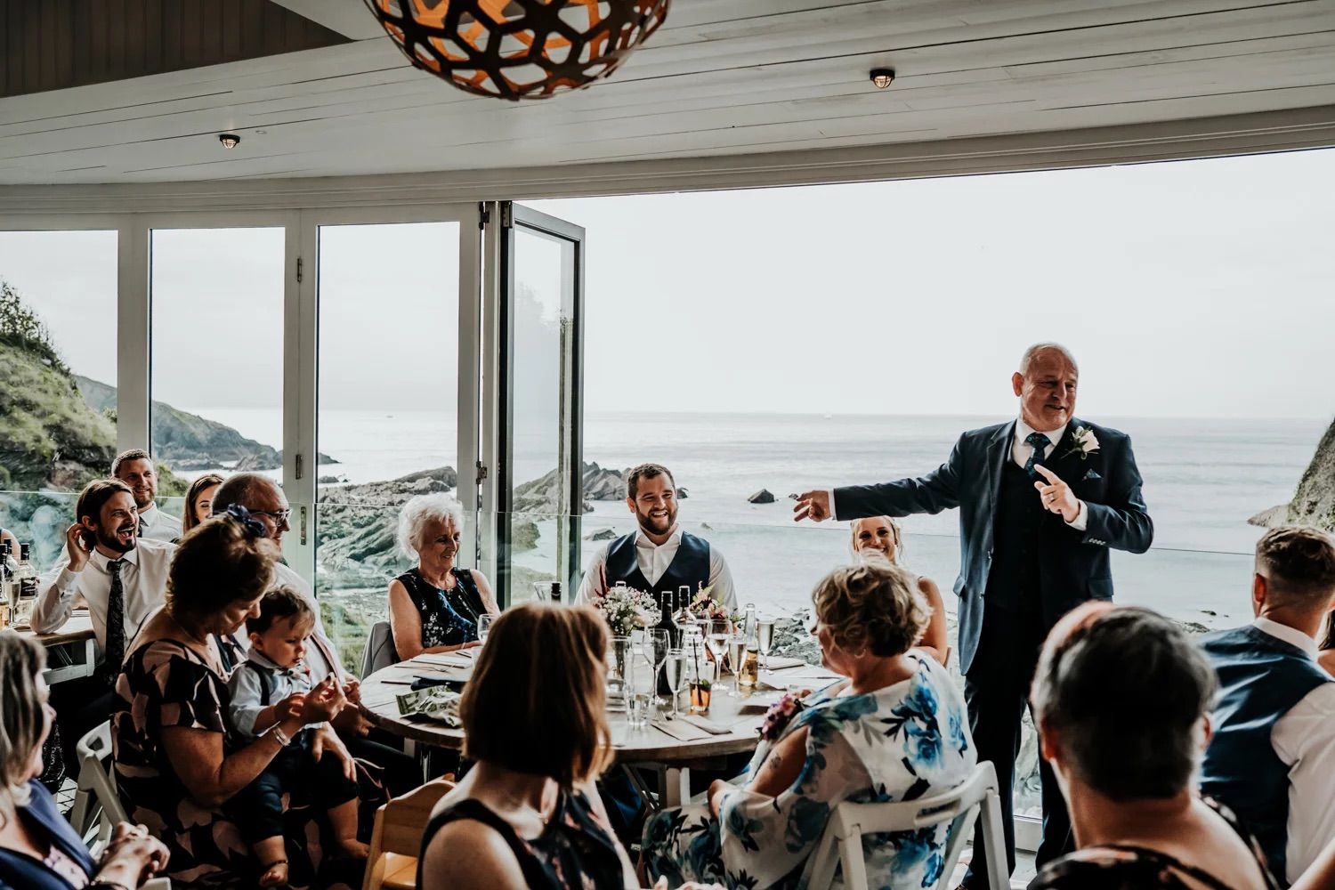 Guests seated at coastal wedding reception venue with ocean views.