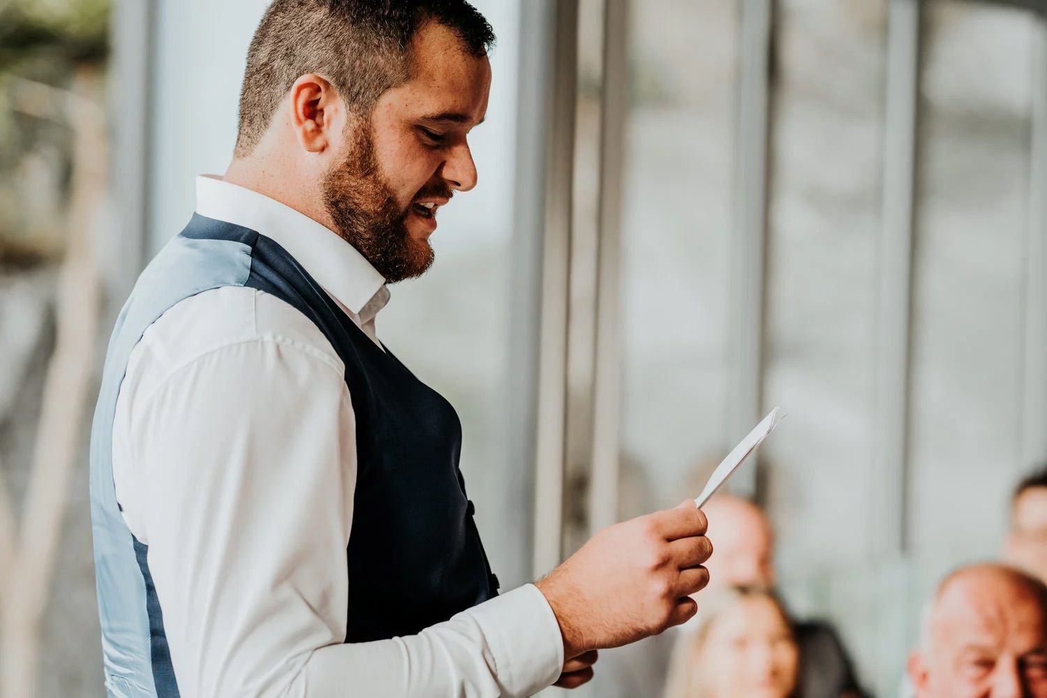 People enjoy a celebration in an indoor reception space with natural lighting.