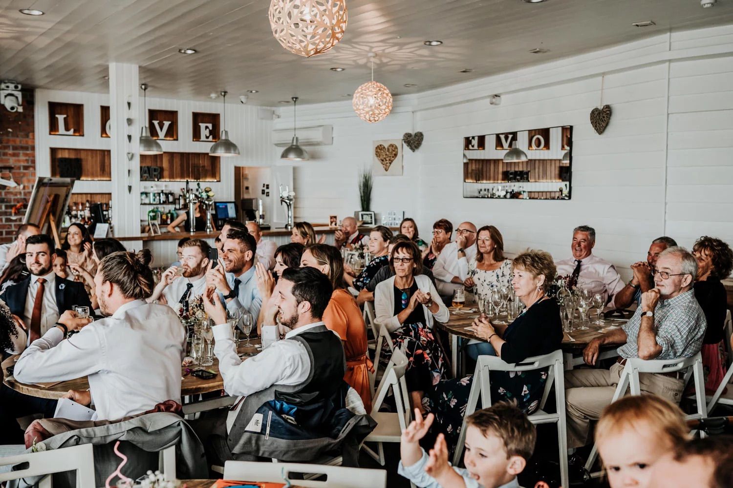 Wedding reception in bright white room with crystal chandeliers and festive celebration.