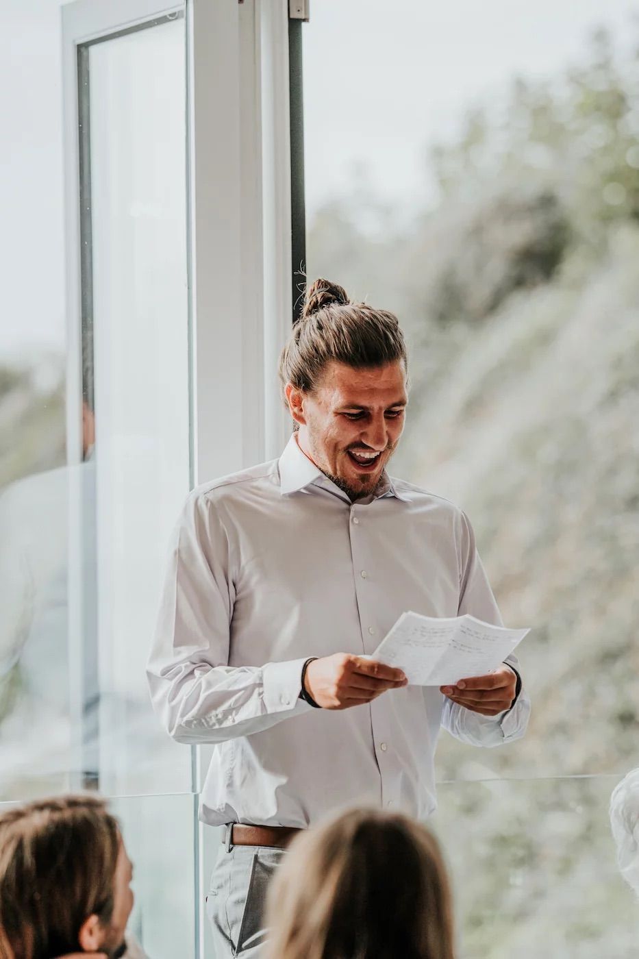 Professional speaker sharing an engaging presentation while laughing with attendees in a bright conference room.