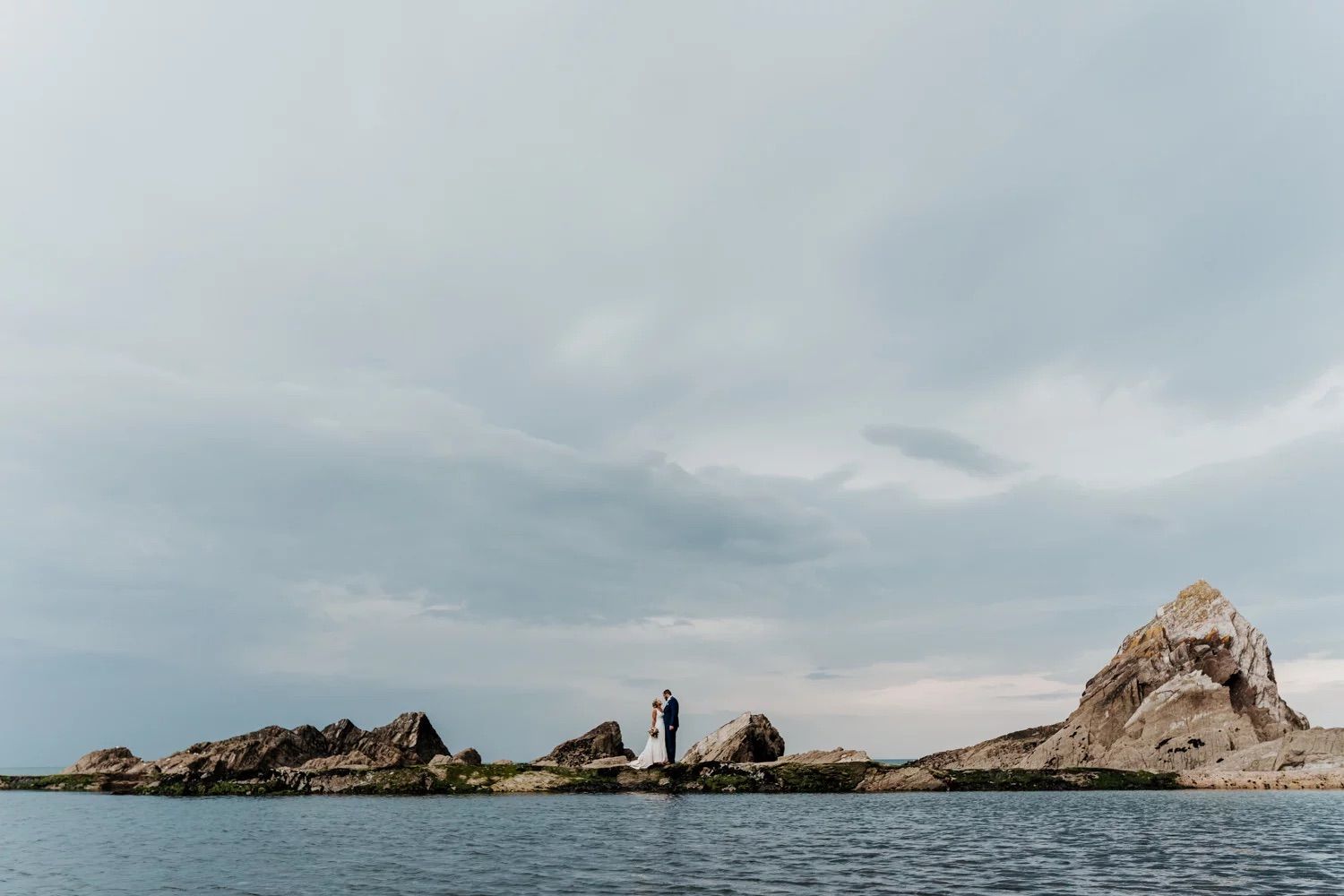 Panoramic view of a rocky coastal landscape with cliffs and ocean under cloudy skies.