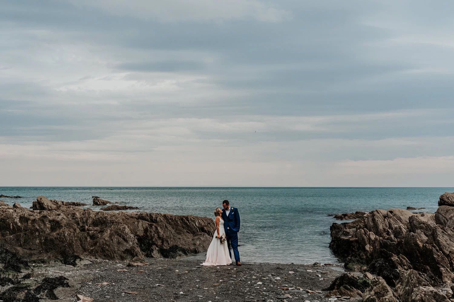 Panoramic sequence of coastal wedding photos showing rocky cliffs and ocean under moody skies.
