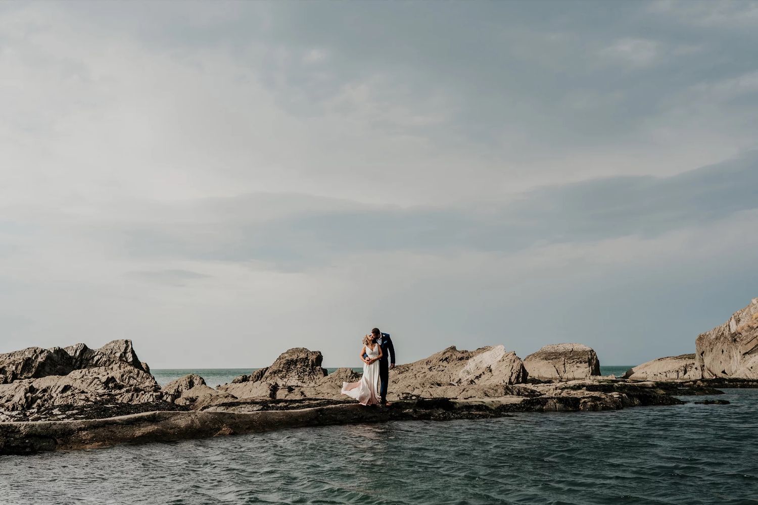 Dramatic coastal landscape with rocky cliffs and ocean views under cloudy skies.