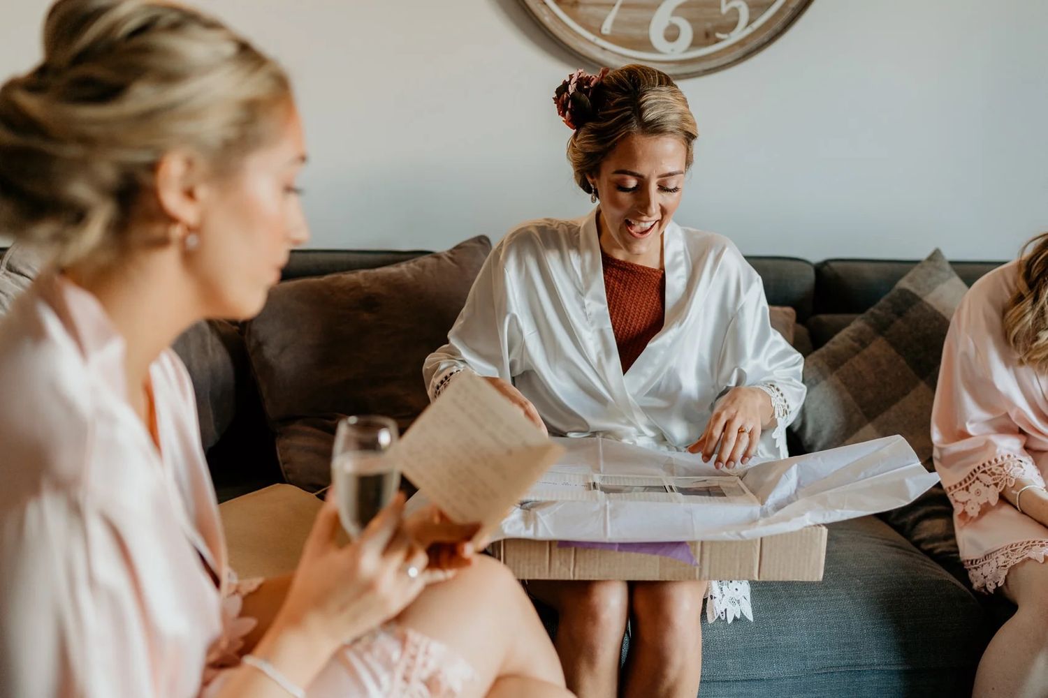 Wedding party getting ready together in white robes while looking at documents in a bright room.