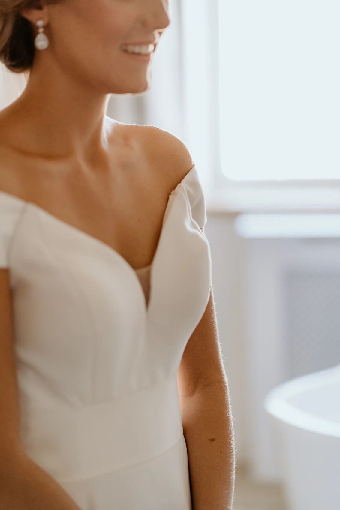 Close up of an elegant white wedding dress with modern architectural neckline details.