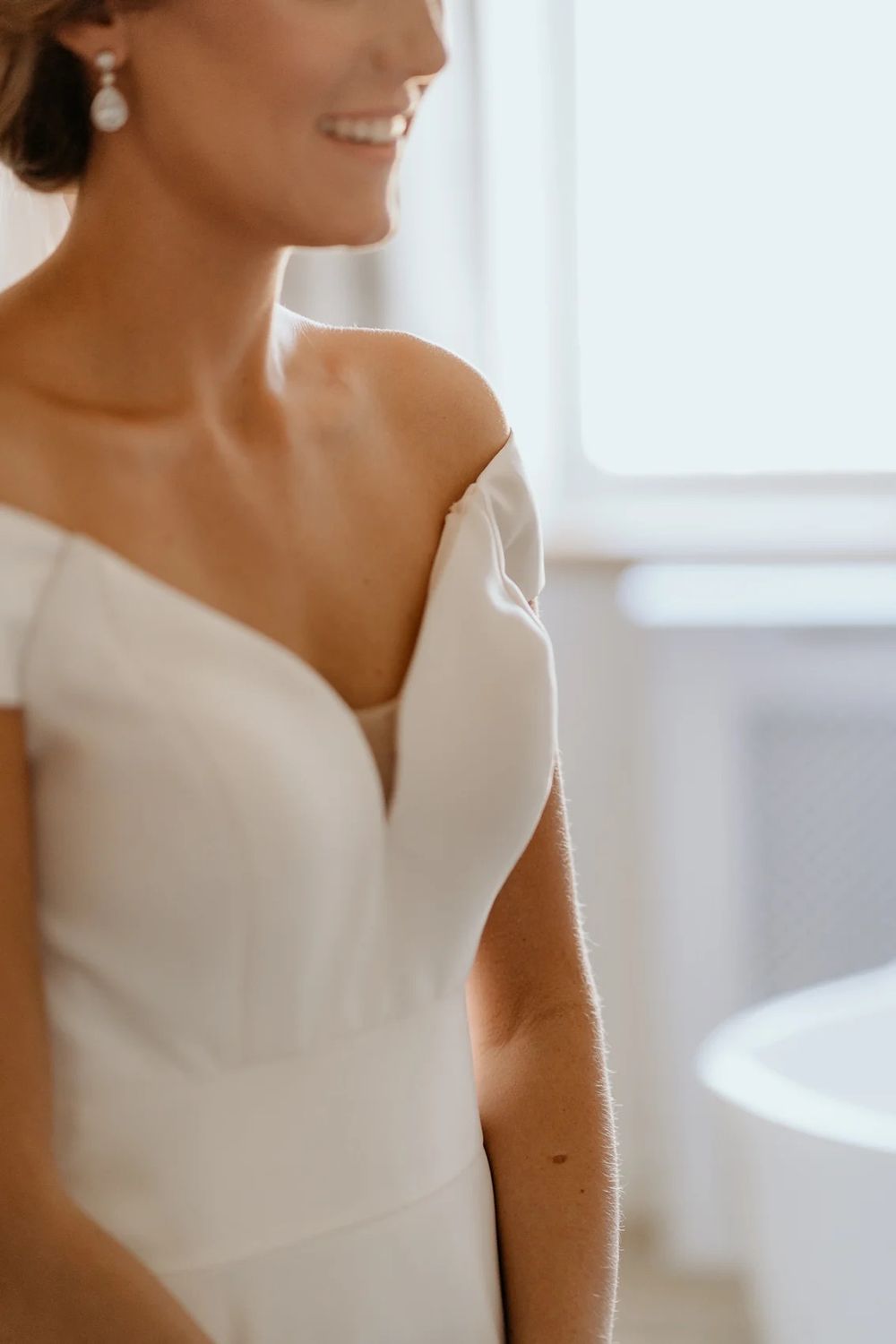 Close up of an elegant white wedding dress with modern architectural neckline details.
