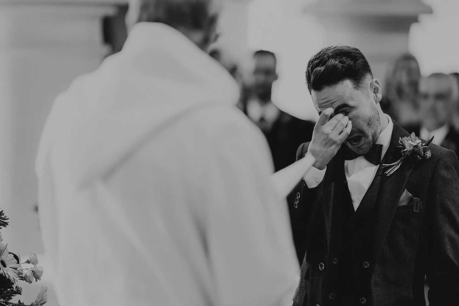 Black and white candid photo showing emotional reactions during wedding ceremony.