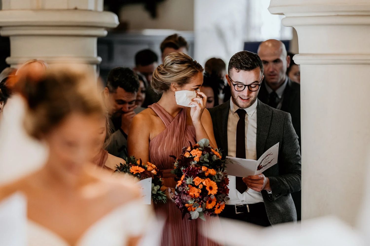 Wedding ceremony attendees watch with emotion as vows are exchanged in church setting.
