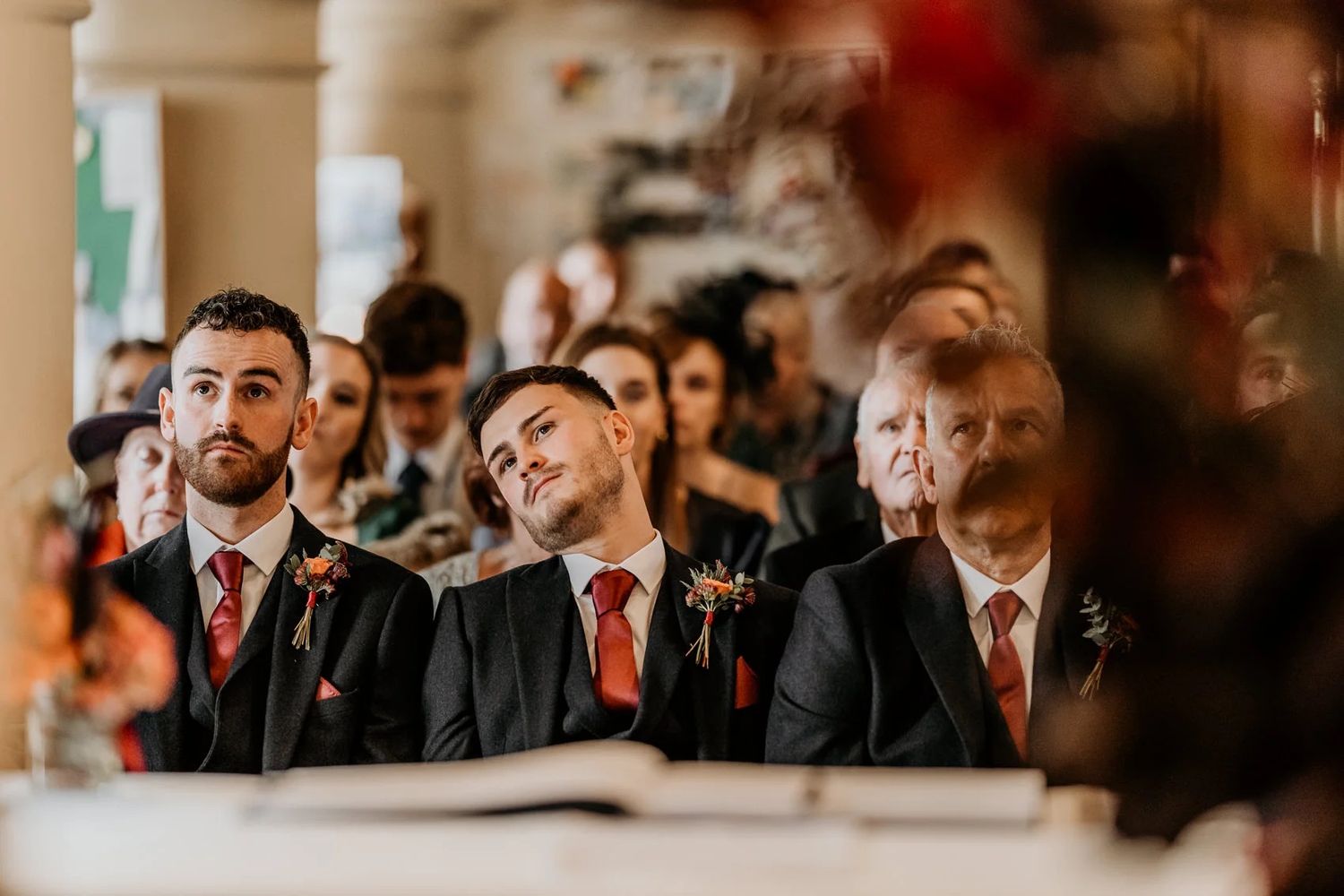 Guests at a wedding ceremony watching with emotional expressions through a soft focus lens.