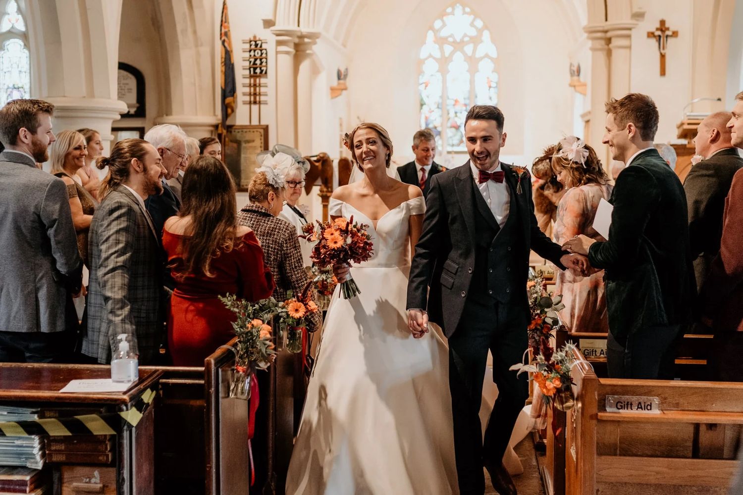Traditional church wedding ceremony with floral decorations and guests seated in wooden pews.
