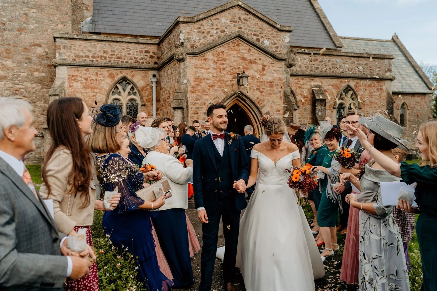 Guests celebrate outside historic brick church building during wedding reception.
