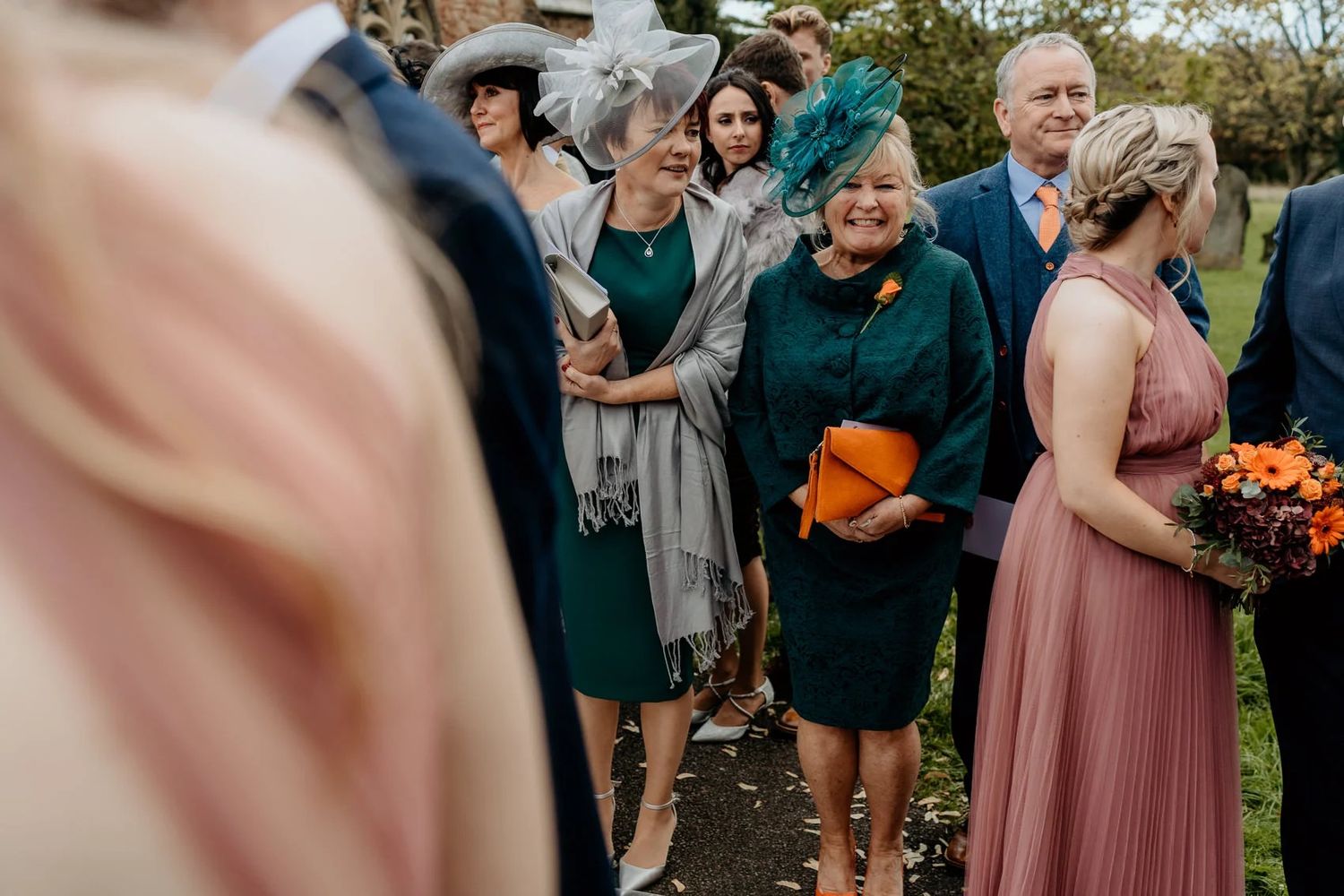 Wedding guests mingling outdoors during a fall celebration with pink bridesmaids dresses.
