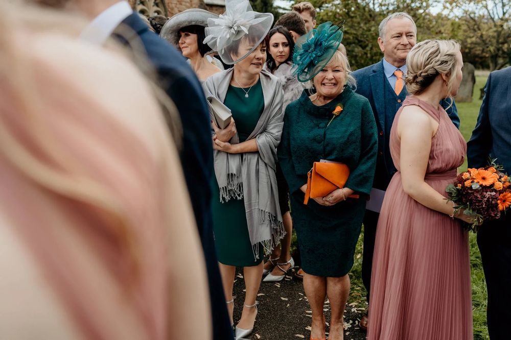 Wedding guests mingling outdoors during a fall celebration with pink bridesmaids dresses.