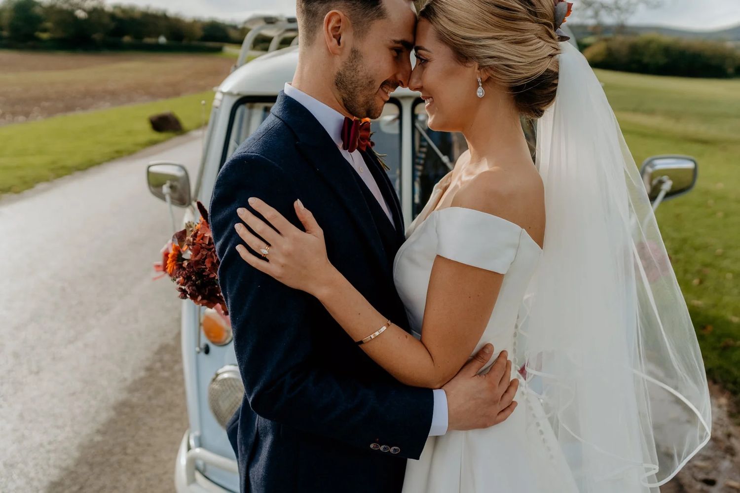 Couple shares romantic outdoor wedding photos in scenic countryside setting.