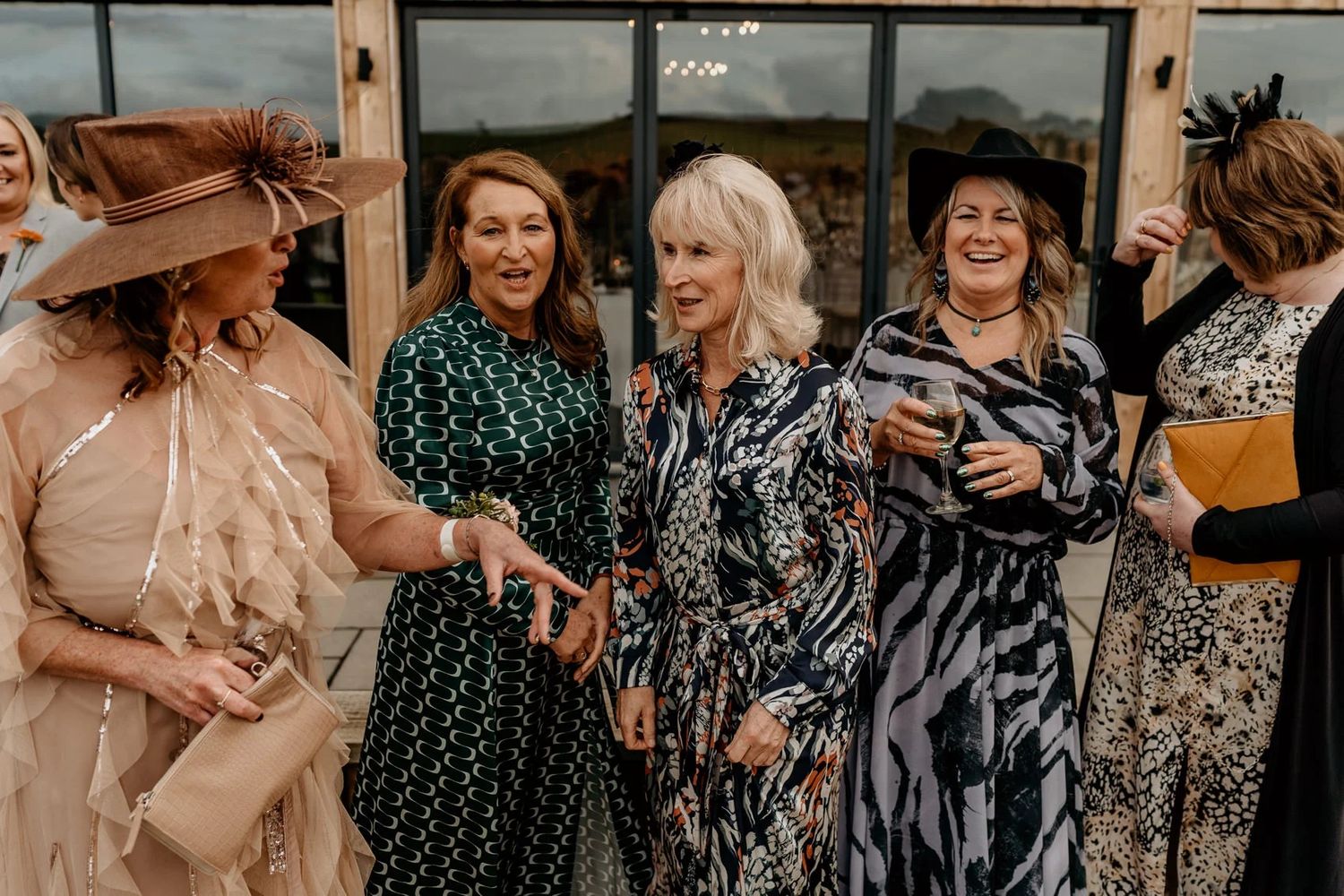 A group of wedding guests in patterned dresses enjoying themselves at an outdoor reception.