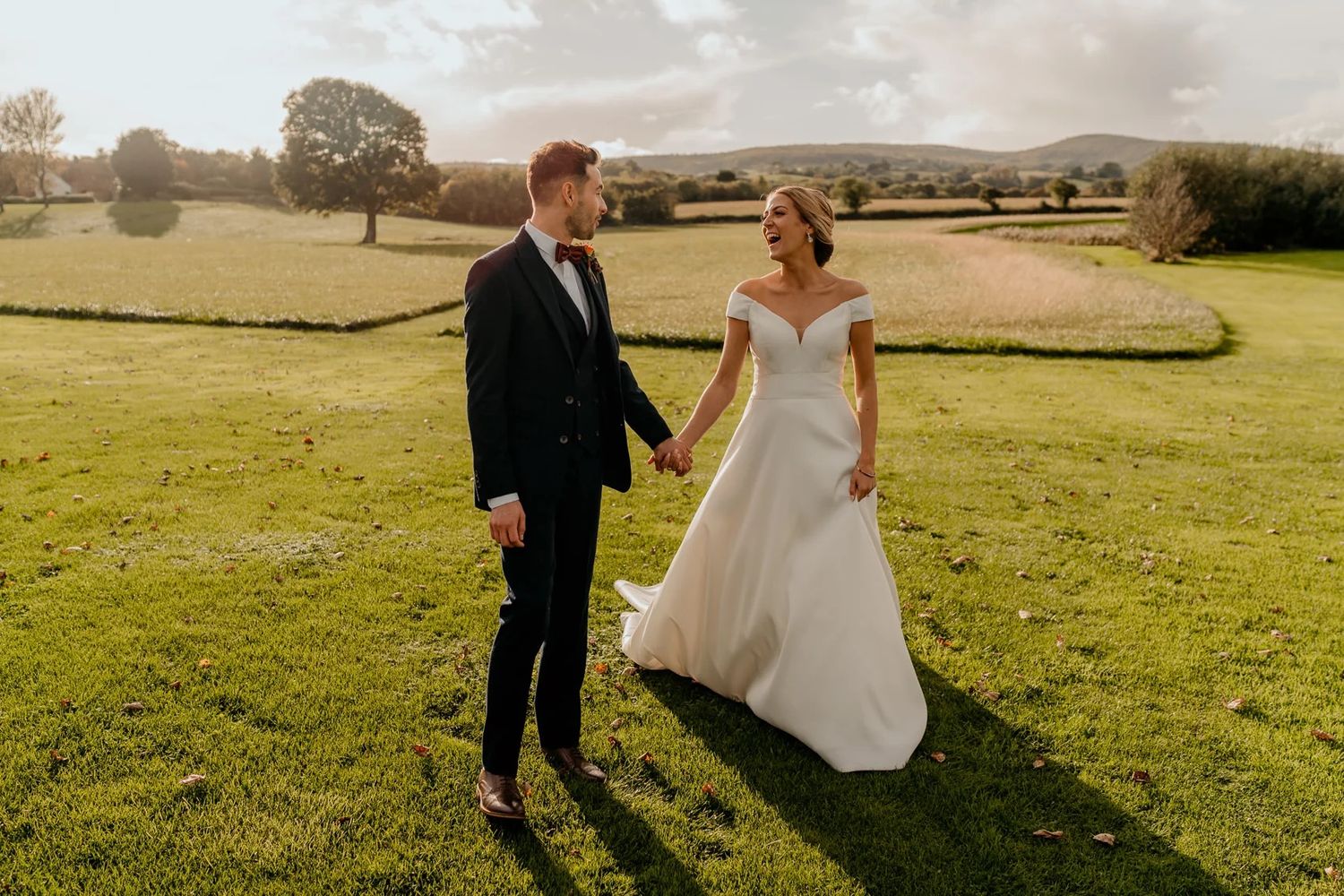 Sunset wedding photos in an open field with rolling hills in the background.