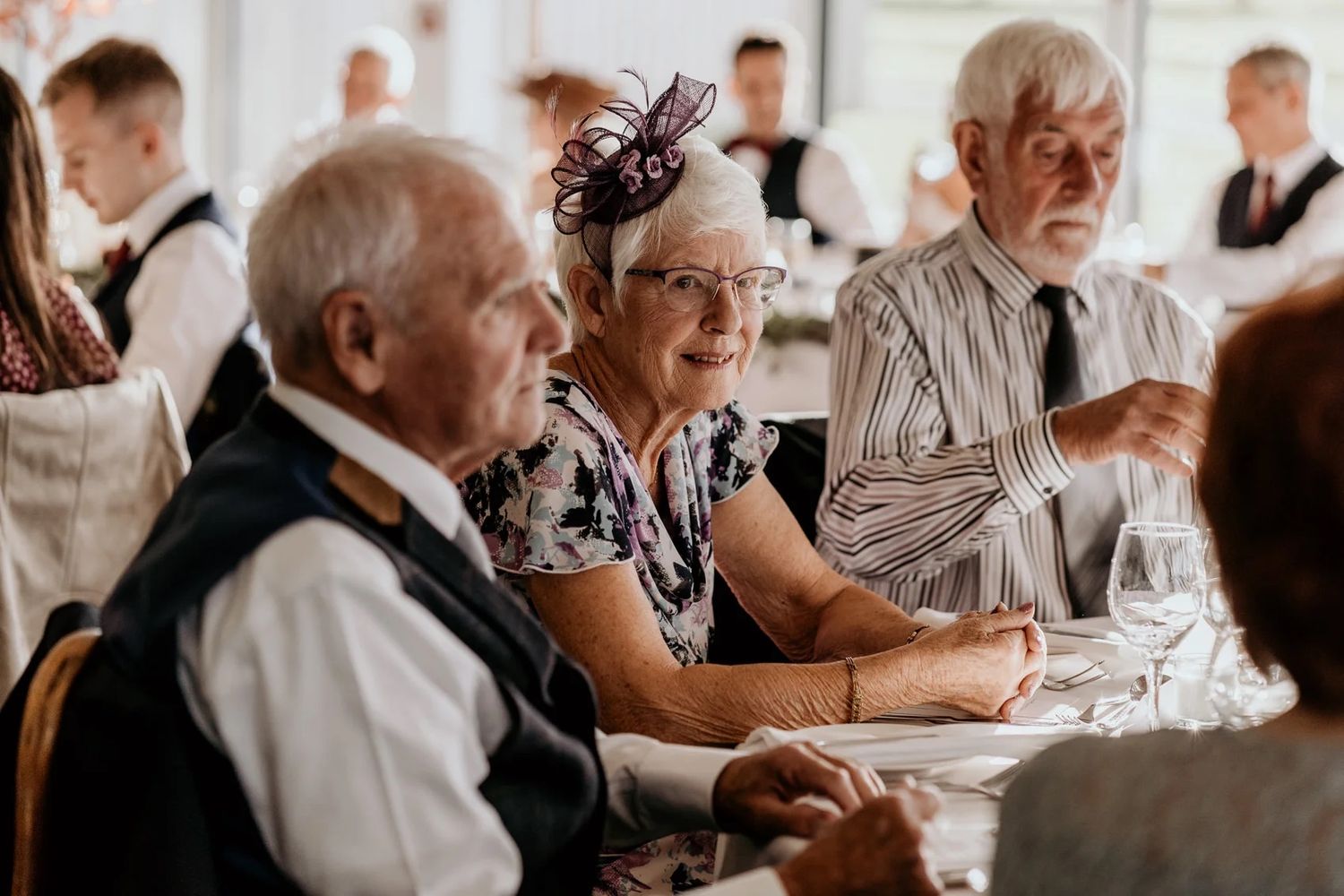 Reception guests enjoying dinner and conversation at elegantly set tables.