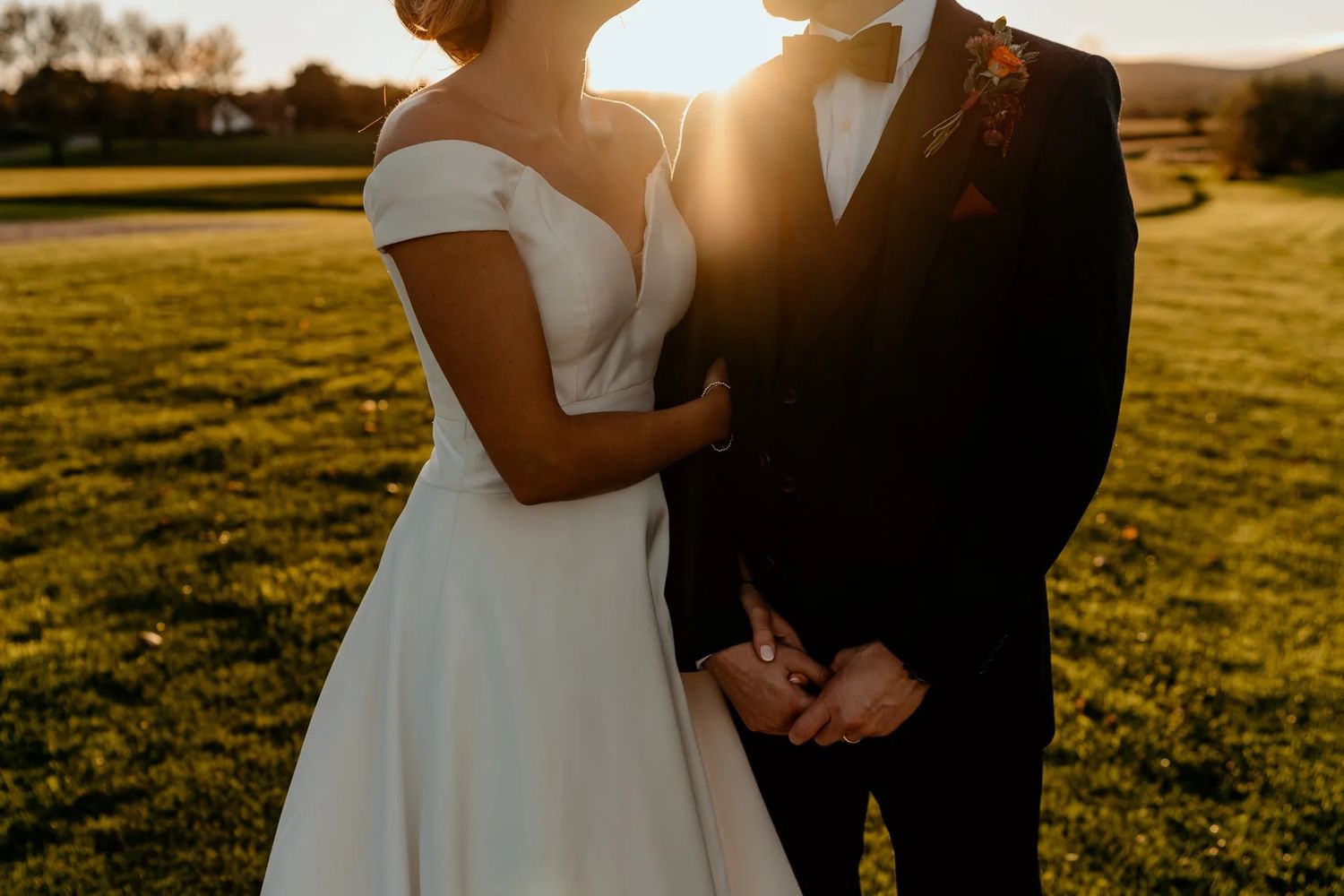 Sunset wedding portrait with couple silhouetted against warm golden sky.