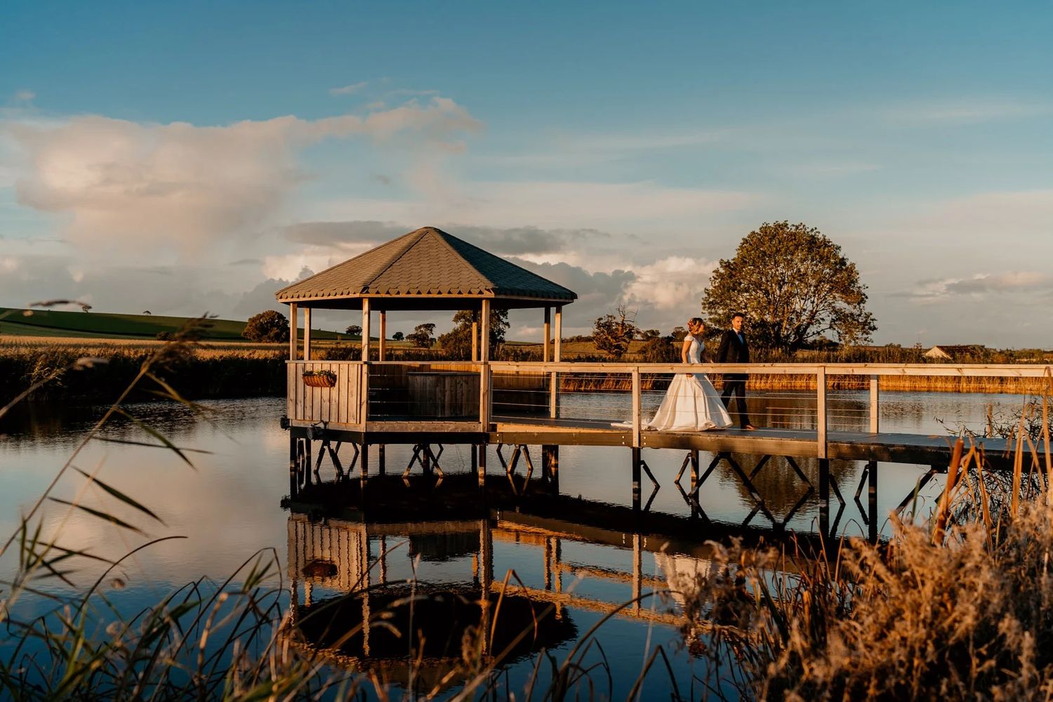 Wooden docks and waterfront structures line a tranquil lake at dusk with a warm sunset glow.