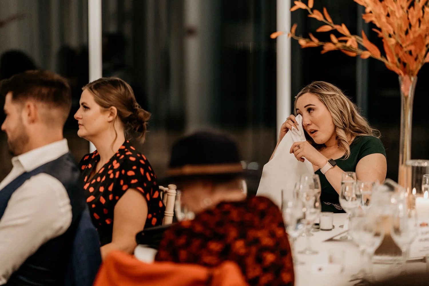 Wedding guests mingle around elegantly decorated tables during an evening reception.
