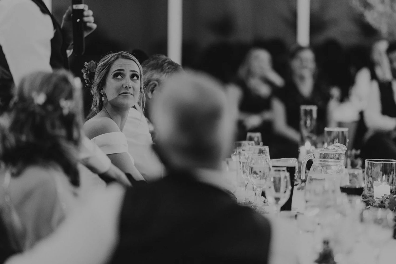 Wedding guests sit at elegant tables during a formal reception dinner celebration.