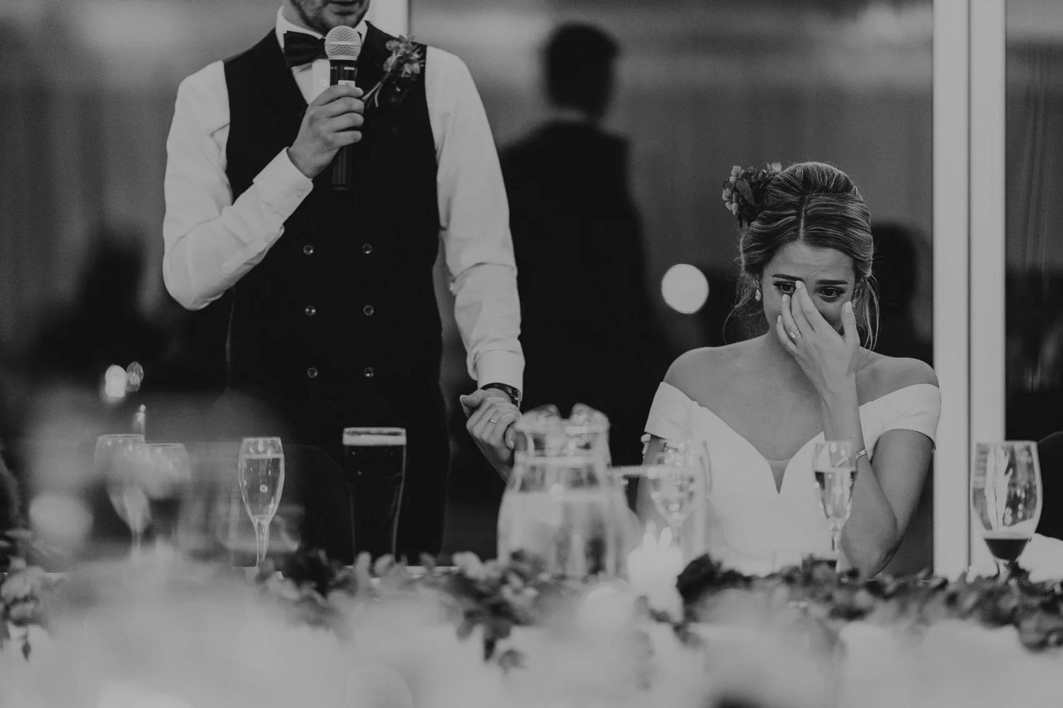 Black and white photo of wedding reception tables set with formal place settings and candles.